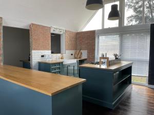 a large kitchen with blue cabinets and a brick wall at Talga Grove in Rothbury