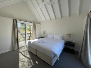 - une chambre avec un grand lit blanc et une fenêtre dans l'établissement Talga Grove, à Rothbury