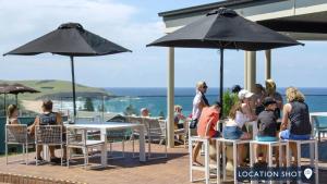 a group of people sitting at tables under umbrellas at Armstrong Ridge in Gerringong