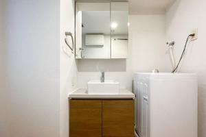 een kleine badkamer met een wastafel en een koelkast bij Luce Takanawa in Tokyo