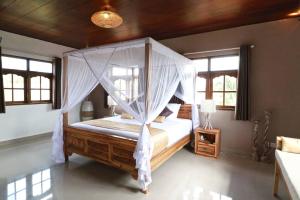 a bedroom with a canopy bed in a room with windows at Villa Santai in Seminyak