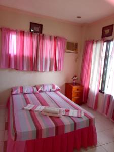 a bedroom with pink curtains and a bed and a dresser at Gallery, air-conditioned room with double bed Kitchen Bathroom Toilet Pools Beaches around the corner in Gabi