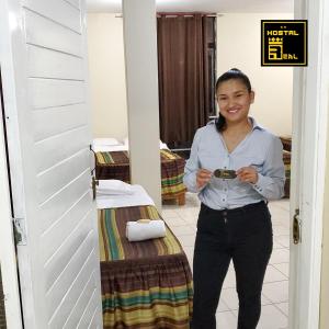 eine Frau, die vor einer Tür steht und ein Handy hält in der Unterkunft Hostal Real Piura - Oficial in Piura