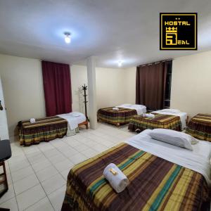 ein Hotelzimmer mit 3 Betten und einem Schild an der Wand in der Unterkunft Hostal Real Piura - Oficial in Piura