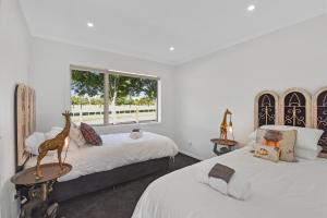 a bedroom with two beds and a giraffe statue on a table at The Whitehouse - Lepperton Holiday Home in New Plymouth
