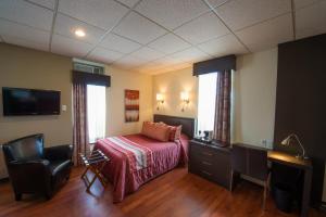 um quarto com uma cama, uma secretária e uma cadeira em Hotel du Fjord em Saguenay