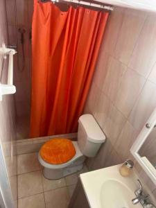 a bathroom with a toilet with an orange shower curtain at Backyard Guesthouse in Miami Gardens