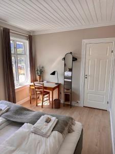 a bedroom with a bed and a table and a desk at Det Gamle Hotellet Guesthouse in Reine