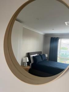 a bedroom with a blue bed and a round mirror at Spacious 5-bed house opposite IGA & Golf Course in Kalgoorlie