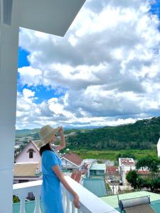 una donna con un vestito blu che si erge su un balcone di Uncle Park's Villa Son Trang 엉클팍 a Da Lat