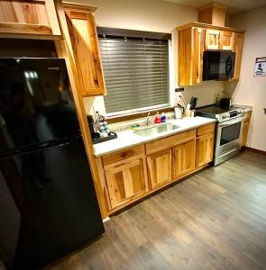 a kitchen with wooden cabinets and a black refrigerator at Bear Mountain - Suite 1 in Grants Pass