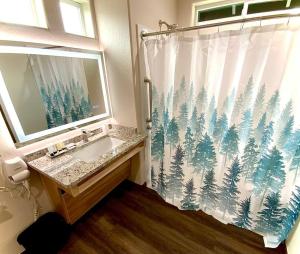 a bathroom with a sink and a shower curtain with trees at Bear Mountain - Suite 1 in Grants Pass