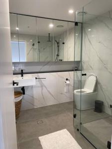 uma casa de banho com uma cabina de duche em vidro, um WC e um lavatório. em Designer 1 BR Apt in Wollongong with Ocean Views em Wollongong