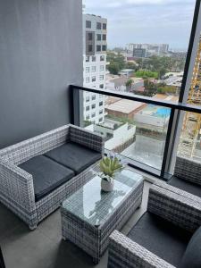 a balcony with a table and wicker chairs and a large window at Designer 1 BR Apt in Wollongong with Ocean Views in Wollongong