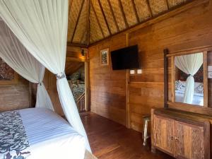 ein Schlafzimmer mit einem Bett und einem Spiegel sowie einem TV in der Unterkunft Sirya Farm House in Meliling