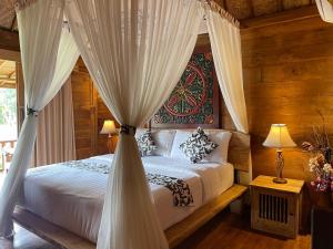 una camera da letto con letto a baldacchino con tende bianche di Sirya Farm House a Meliling