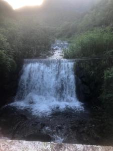 une cascade sur le côté d'une montagne avec une rivière dans l'établissement 秋憶木屋, à Gukeng