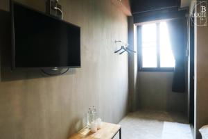 a room with a flat screen tv on a wall at B+Arch House / Hotel&Cafe in Chiang Mai