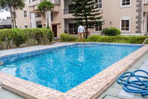 a man is standing next to a swimming pool at Ebrina One Bedroom in Port Harcourt