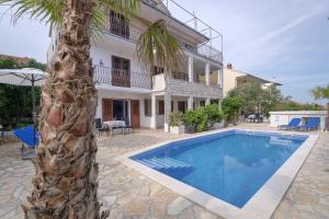 a villa with a palm tree and a swimming pool at Apartments Priko in Stari Grad
