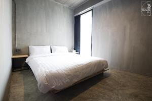 a bedroom with a large bed with a window at B+Arch House / Hotel&Cafe in Chiang Mai