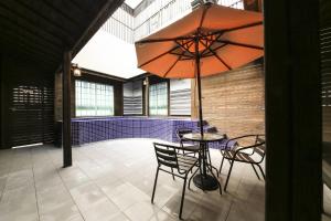 a patio with a table and chairs and an umbrella at Almond Hotel Gupo Station in Busan