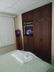 a bedroom with a bed and a tv and cabinets at Villa Amoblada en Urbanización in Machala