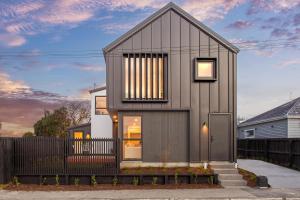 a small house with a black exterior at Chatham Street - Christchurch Holiday Homes in Christchurch