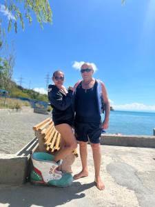 Ein Mann und eine Frau stehen auf einer Bank in der Nähe des Ozeans in der Unterkunft EDEM SEVAN in Sewan