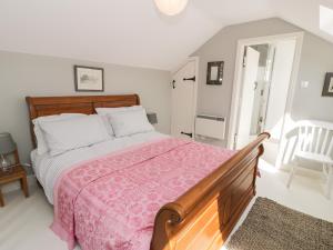 a bedroom with a large bed with a pink blanket at Gelli Bach at Gelli Las in Llanbedr