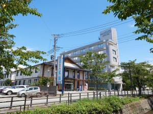 Tabist Onsen Hotel Toyo في Fuefuki: مبنى فيه سيارات تقف امامه