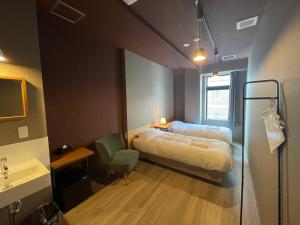 a small room with a bed and a sink and a bathroom at WISE OWL HOSTELS SAPPORO in Sapporo
