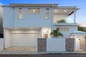 a white house with a white garage door at LEO2-SOPHISTICATED, BEACH HOLIDAY HOME in Alexandra Headland