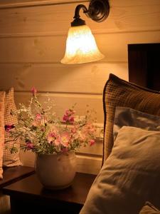a lamp and a vase with flowers on a table next to a bed at green island in Ma'ale Gamla