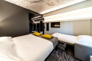 two beds in a hotel room with yellow pillows at ibis Tallinn Center in Tallinn