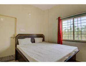 a bed in a bedroom with a red curtain at Vedanta Hotel, Bareilly in Bareilly