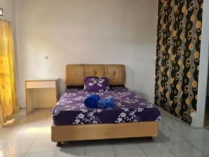 Schlafzimmer mit einem Bett mit lila Bettwäsche und blauen Kissen in der Unterkunft Kampung Istal Villa Pamijahan in Cireungkong