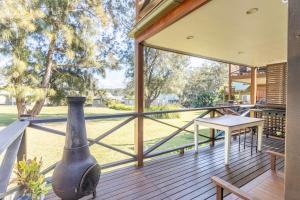 Coral Cottage في Berrara: شرفة كبيرة مغطاة بطاولة ومزهرية