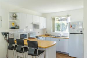 a kitchen with white cabinets and a wooden counter top at Coral Cottage in Berrara
