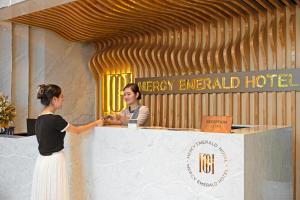 two women are standing at a reception desk at Mercy Emerald Hotel in Danang