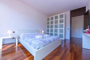 a bedroom with a white bed and a wooden floor at Lugano Centro- Happy Rentals in Lugano
