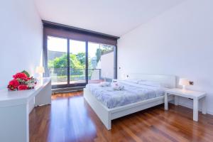 a white bedroom with a bed and a large window at Lugano Centro- Happy Rentals in Lugano