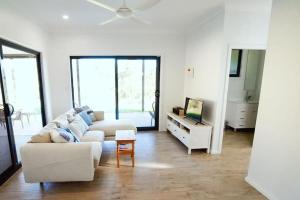 a living room with a white couch and a table at Hilltop Retreat - best of both worlds: Beach/farm in Pillar Valley