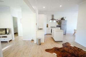 a large white kitchen with a wooden floor at Hilltop Retreat - best of both worlds: Beach/farm in Pillar Valley