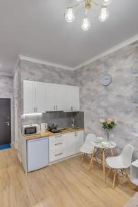 - une cuisine avec des placards blancs, une table et des chaises dans l'établissement Asaapart Vernyi Room 1, à Almaty