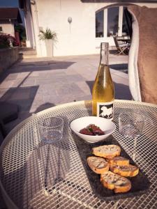 a table with a bottle of wine and a bowl of food at L'adret du bois in Sames