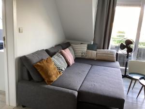 a couch with pillows on it in a living room at Just like home De Haan aan Zee in De Haan