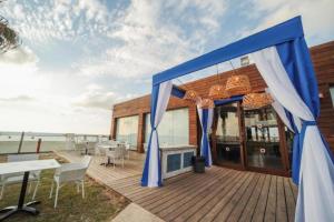 un restaurante con cortinas azules en una terraza de madera en Nachsholim Kibbutz Country Lodging en Nachsholim