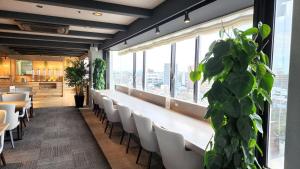 un ristorante con sedie bianche e una grande finestra di Platon Hotel Yokkaichi a Yokkaichi