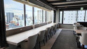 una habitación con una mesa larga, sillas y ventanas en Platon Hotel Yokkaichi, en Yokkaichi